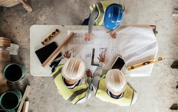 Architect, construction and blueprint with an engineer and designer team working on a building site from above. Meeting, planning and architecture with a design group in collaboration on a project