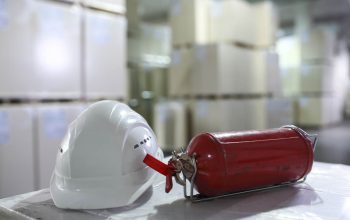 Hardhat on a box in warehouse with fire extinguisher in a big warehosue.